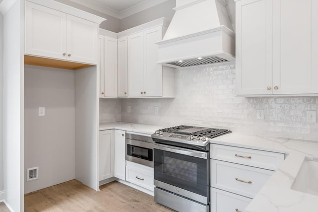 3180 Long Branch Cir, Franklin, TN 37064 - kitchen featuring custom range hood, stainless steel range with gas cooktop, light stone counters, light wood finished floors, and white cabinets