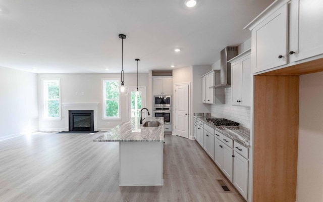 156 John T Alexander Blvd, Hendersonville, TN 37075 - kitchen featuring wall chimney exhaust hood, stainless steel appliances, light wood finished floors, light stone countertops, and open floor plan