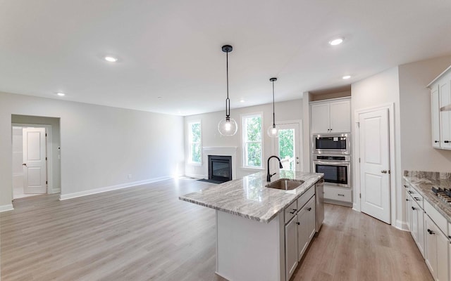 156 John T Alexander Blvd, Hendersonville, TN 37075 - kitchen with a sink, appliances with stainless steel finishes, a glass covered fireplace, light wood-type flooring, and a center island with sink