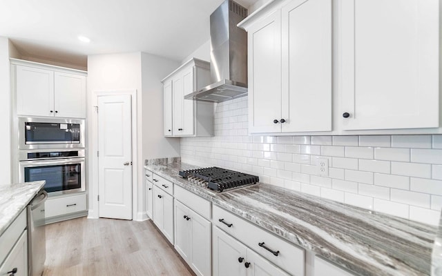 156 John T Alexander Blvd, Hendersonville, TN 37075 - kitchen featuring appliances with stainless steel finishes, wall chimney range hood, light wood-style floors, light stone countertops, and backsplash