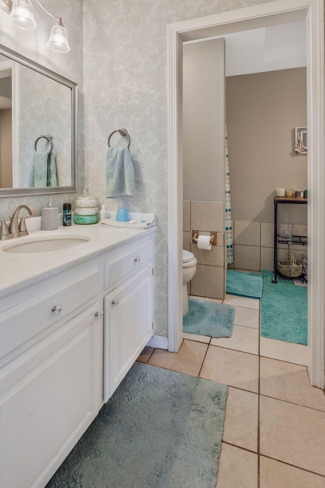 bathroom with toilet, tile patterned flooring, vanity, and wallpapered walls
