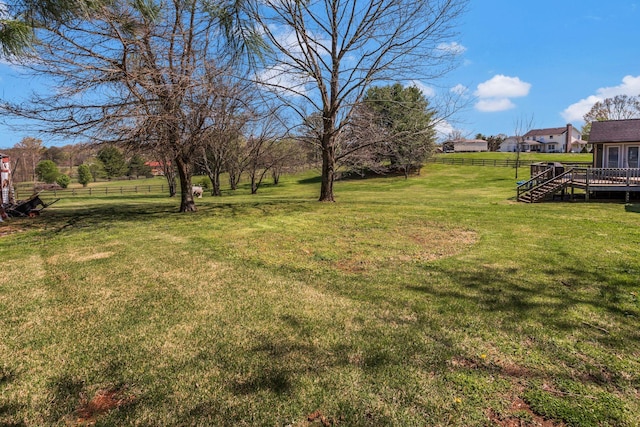 view of yard with a wooden deck, fence, and a rural view