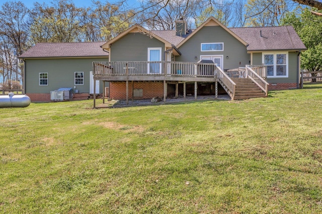 back of house featuring a shingled roof, stairway, a deck, and a lawn