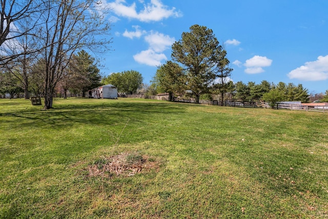 view of yard with an outbuilding, fence, a rural view, and a shed