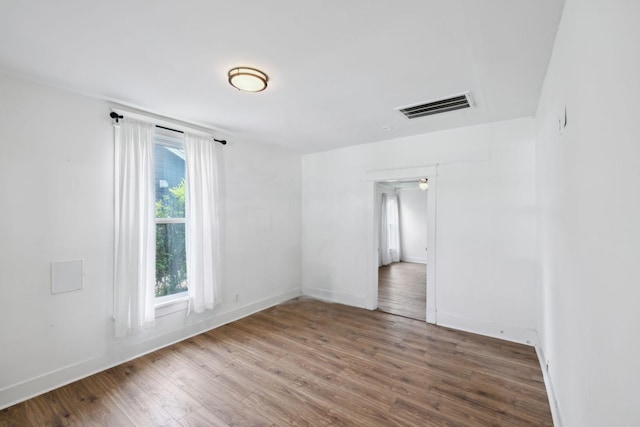 unfurnished room featuring wood finished floors, baseboards, and visible vents