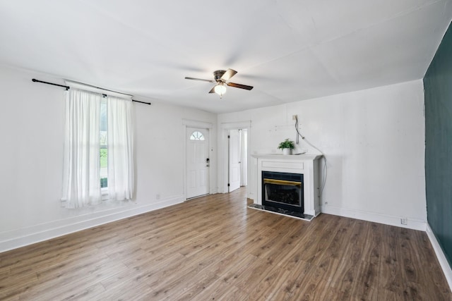 unfurnished living room with a tile fireplace, baseboards, wood finished floors, and ceiling fan