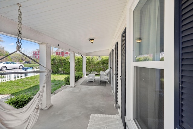 view of patio featuring a porch and fence