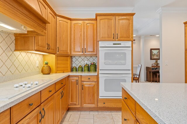 kitchen with light tile patterned floors, wall chimney exhaust hood, white appliances, ornamental molding, and backsplash