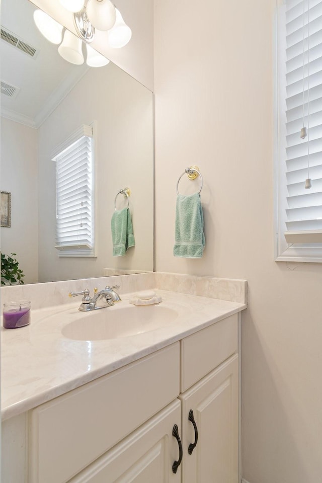 bathroom featuring an inviting chandelier, vanity, ornamental molding, and visible vents