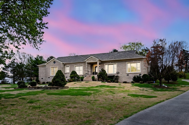 view of front facade with brick siding and a front lawn