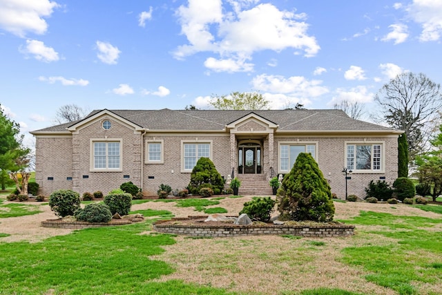 ranch-style home with roof with shingles, a front yard, and brick siding