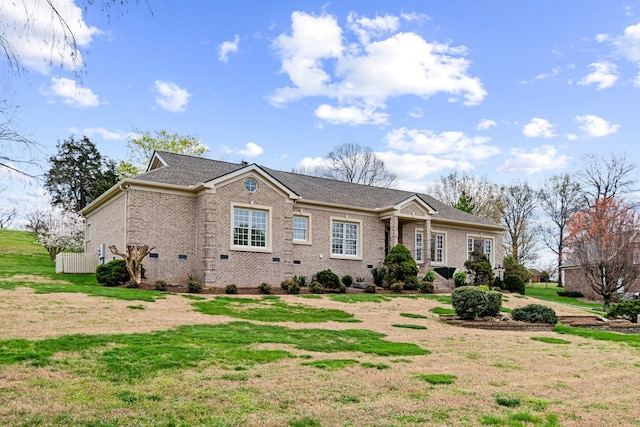 view of front of house featuring a front yard, brick siding, and roof with shingles