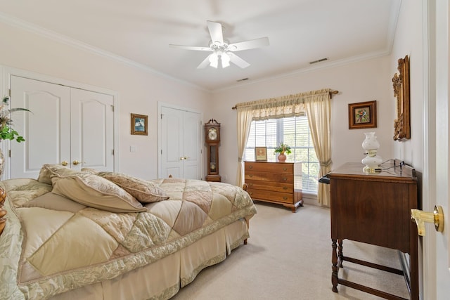 bedroom with ceiling fan, ornamental molding, visible vents, light carpet, and multiple closets