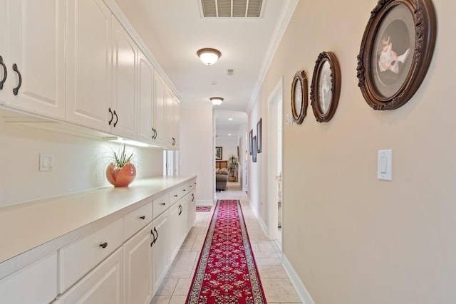 hall featuring crown molding, visible vents, baseboards, and light tile patterned floors