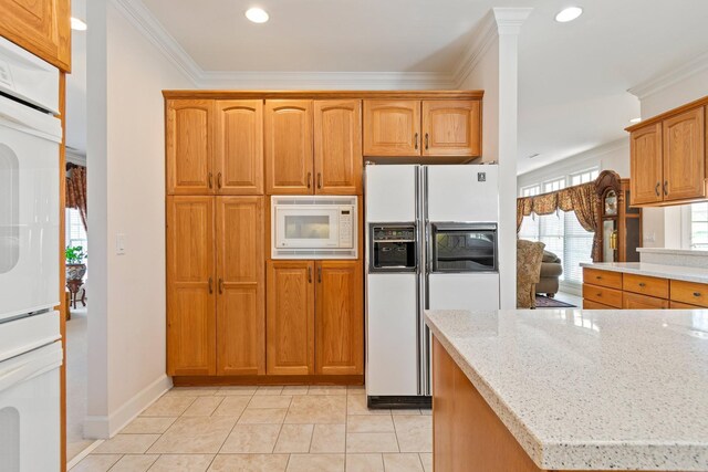 kitchen with crown molding, light tile patterned floors, white appliances, and light stone counters