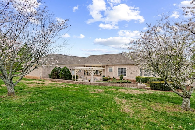 back of house featuring roof with shingles, a pergola, a patio area, brick siding, and a lawn