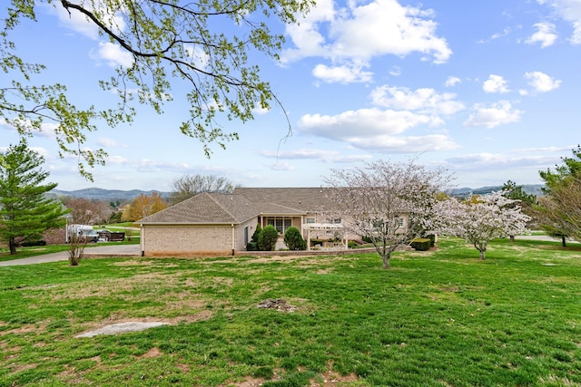 view of front facade featuring a front yard, brick siding, and a mountain view