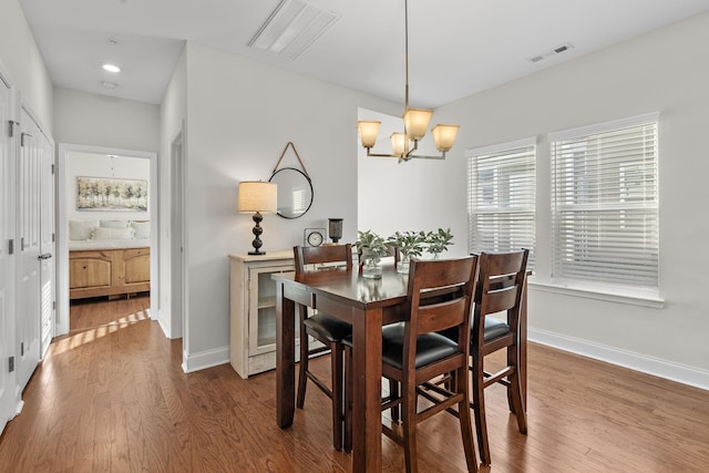 dining space with visible vents, baseboards, a chandelier, and wood finished floors