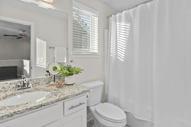 bathroom with toilet, curtained shower, vanity, and ceiling fan