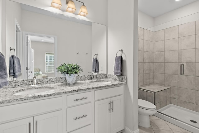 full bathroom with a shower stall, double vanity, a sink, and toilet
