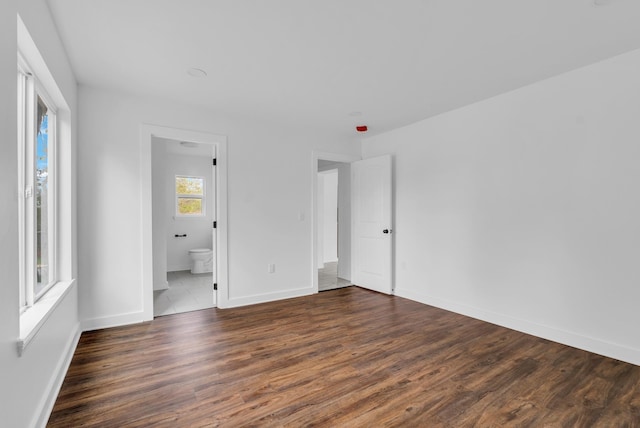 unfurnished bedroom featuring baseboards, connected bathroom, and wood finished floors