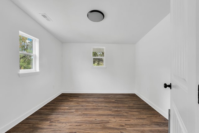 empty room featuring baseboards, dark wood finished floors, and visible vents