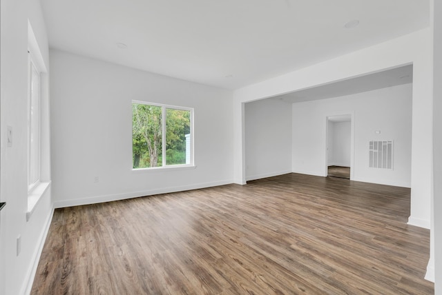 empty room featuring wood finished floors, baseboards, and visible vents
