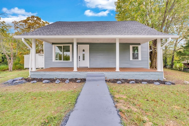 view of front of property with a porch, roof with shingles, and a front yard