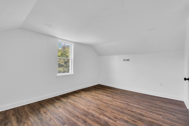 additional living space featuring visible vents, baseboards, dark wood-style floors, and vaulted ceiling