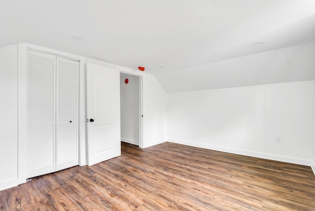additional living space featuring wood finished floors, baseboards, and vaulted ceiling