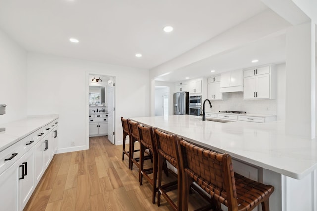 1048 Edgewater Cir, Gallatin, TN 37066 - kitchen featuring white cabinetry, light wood-style floors, appliances with stainless steel finishes, and a kitchen bar