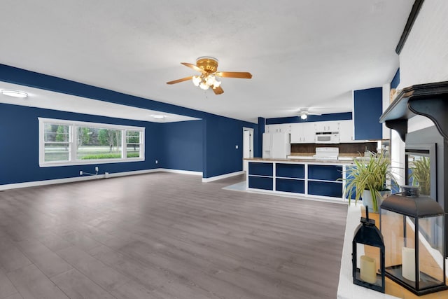 unfurnished living room featuring baseboards, a ceiling fan, and wood finished floors