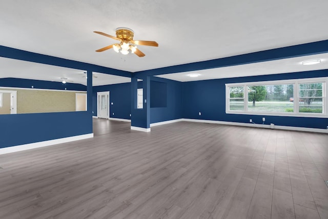 unfurnished living room featuring baseboards, a ceiling fan, and wood finished floors