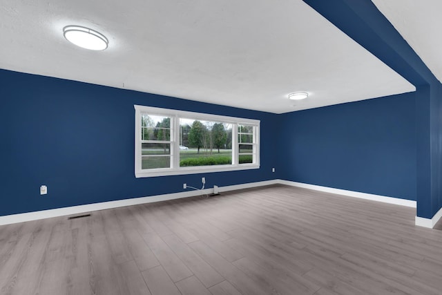 spare room with wood finished floors, baseboards, and visible vents