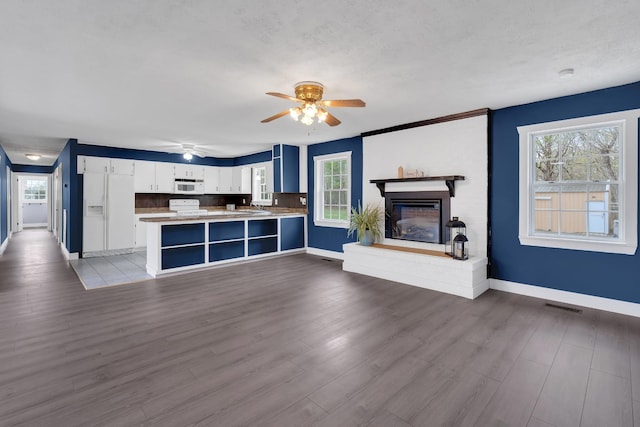unfurnished living room featuring visible vents, ceiling fan, wood finished floors, and baseboards