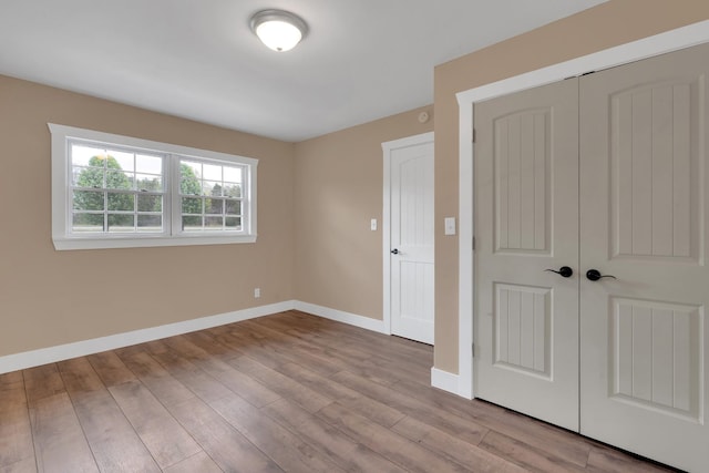 unfurnished bedroom with a closet, baseboards, and wood finished floors