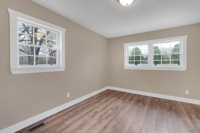 empty room featuring visible vents, baseboards, and wood finished floors