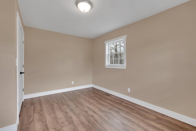 empty room featuring visible vents, baseboards, and wood finished floors