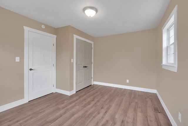 unfurnished bedroom with visible vents, light wood-style flooring, and baseboards