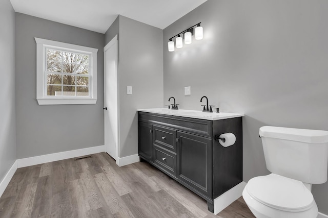 bathroom featuring vanity, baseboards, toilet, visible vents, and wood finished floors
