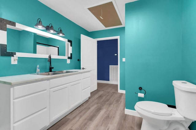 bathroom featuring vanity, visible vents, toilet, wood finished floors, and baseboards