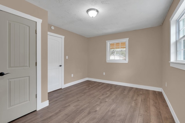 empty room featuring baseboards, wood finished floors, and a textured ceiling