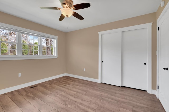 unfurnished bedroom with ceiling fan, light wood-type flooring, a closet, visible vents, and baseboards