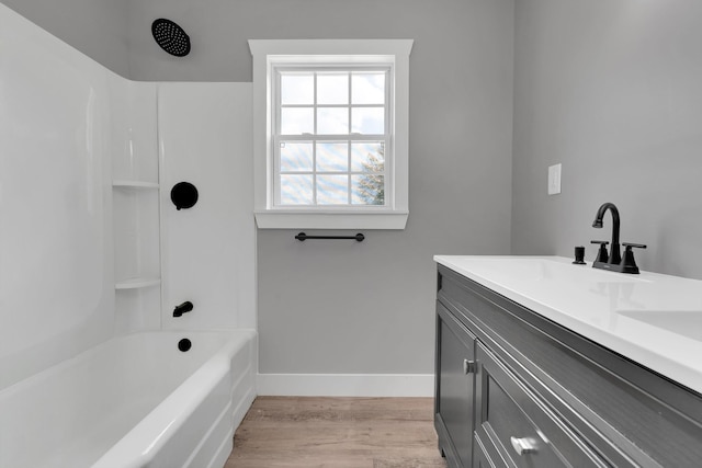 bathroom featuring shower / bathtub combination, wood finished floors, a sink, double vanity, and baseboards