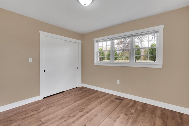 unfurnished bedroom with light wood-style flooring, a closet, and baseboards