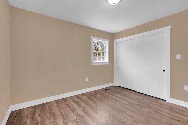 unfurnished bedroom with a closet, light wood-style floors, and baseboards