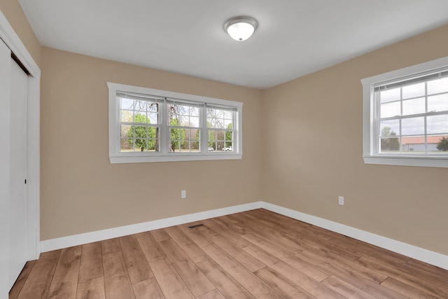 unfurnished bedroom with a closet, baseboards, and multiple windows