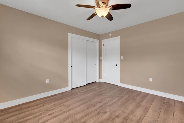 unfurnished bedroom with light wood-style floors, a closet, ceiling fan, and baseboards