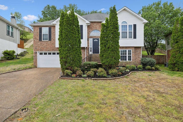 raised ranch with brick siding, fence, a garage, and driveway