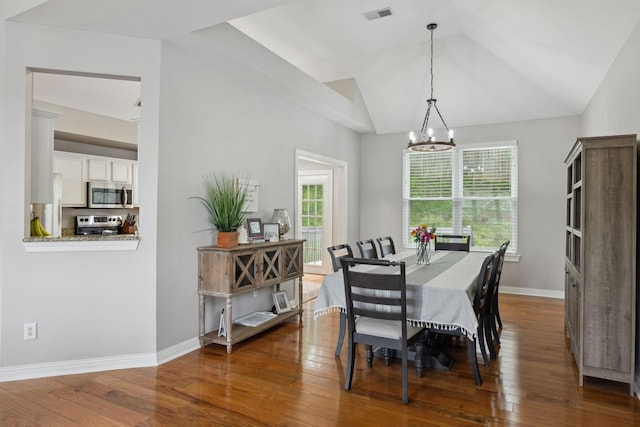 dining space with a wealth of natural light, a notable chandelier, dark wood-type flooring, and visible vents